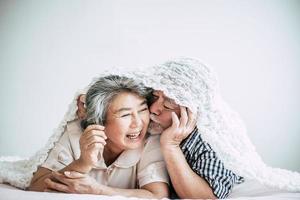 Happy senior couple laughing in bedroom photo