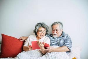 pareja de ancianos acostada en la cama y leyendo un libro