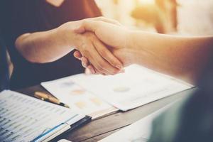 Close-up of two business people shaking hands while sitting at the working place photo