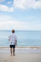 Hombre inconformista camina sobre el fondo de la hermosa playa con nubes blancas y cielo agradable foto