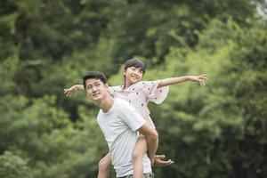 Father carrying daughter on back in the park photo