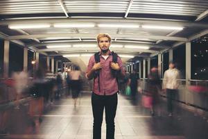 Handsome bearded man with backpack standing on the street traveling at night photo