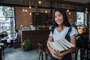 mujer joven sonriente sosteniendo libros foto