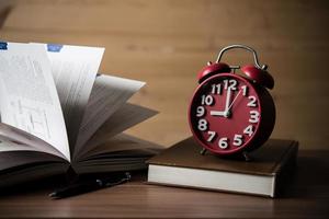 Books and alarm clock on wooden table photo