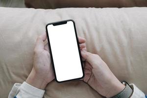 persona sosteniendo un teléfono móvil con pantalla en blanco foto