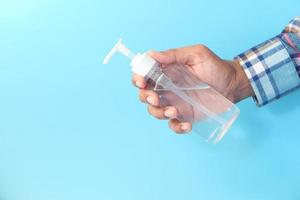 Close up of a man holding hand sanitizer gel on blue background photo