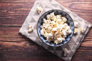 Popcorn in a bowl on wooden table photo