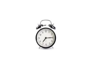 Reloj despertador negro clásico aislado sobre un fondo blanco.