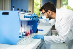 Young researcher with protective goggles checking test tubes in flocculator photo