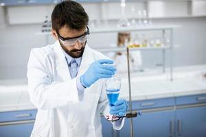 Researcher working with blue liquid at laboratory glass