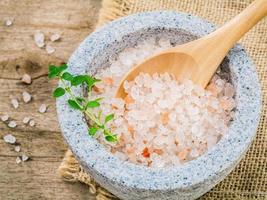 Himalayan pink salt in mortar with thyme on hemp sack background. Himalayan salt commonly used in cooking and for bath products such as bath salts. photo