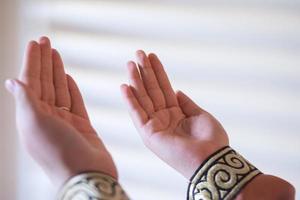 Hands of a Muslim or Islamic woman gesturing while praying at home photo