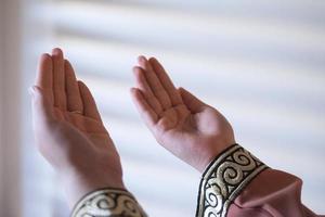 Hands of a Muslim or Islamic woman gesturing while praying at home photo