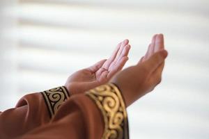 Hands of a Muslim or Islamic woman gesturing while praying at home photo