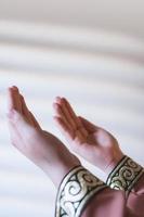 Hands of a Muslim or Islamic woman gesturing while praying at home photo