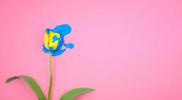 Acrílico de color azul goteando sobre flor de tulipán amarillo foto