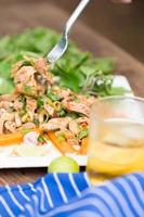 Hot and spicy grilled pork salad on white plate on wooden table photo