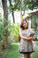 Happy young woman standing and holding notebooks at home garden photo