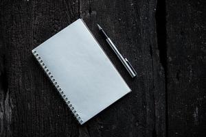 Cuaderno con bolígrafo sobre fondo de textura de madera foto