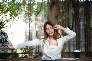 Young businesswoman stretching herself and yawning at workplace photo