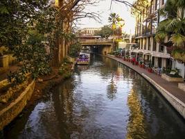 Boat on the San Antonio River next to a restaurant and hotel photo