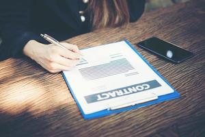 Happy business woman signing a document at desk working at home photo