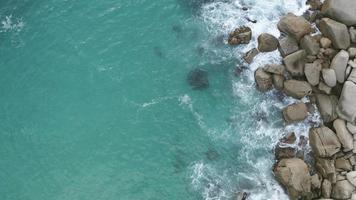 foto aérea de águas profundas do oceano azul e ondas espumosas. as ondas do mar quebram nas rochas da costa criando uma explosão de água video