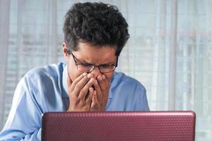 Man sneezing while working at a desk photo