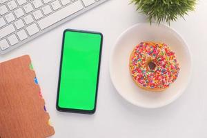 Top view of smart phone and donut on desk top photo