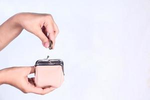 Putting coins into a coin purse on white background photo