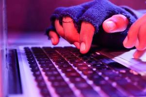 Close up of hacker hand stealing data from laptop photo