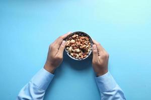 Bowl of mixed nuts on blue background photo