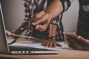 Close-up of business people working with strategy diagrams on wooden desk in office photo