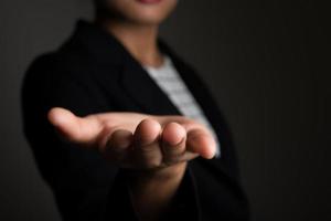 Business woman's hand showing blank area for sign or copyspace, isolated on black background photo