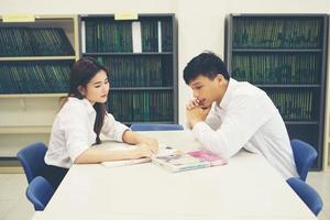 Young Asian student couple at the library reading a book together photo