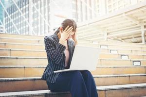 mujer de negocios estresada mientras usa la computadora portátil en los pasos foto