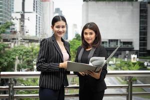 Businesswomen discussing paperwork together against railing photo