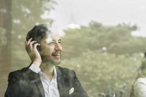 Young businessman using smartphone while working on his laptop in office photo