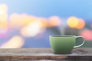 Taza de café verde sobre la mesa con fondo bokeh estilo oscuro foto