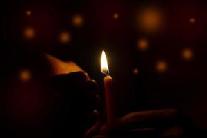 Hand holding a candle in the dark light with light bokeh