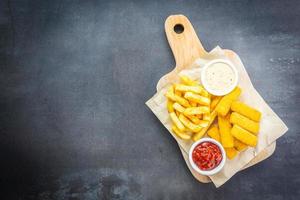Fish finger and french fries with ketchup and mayonnaise sauce photo