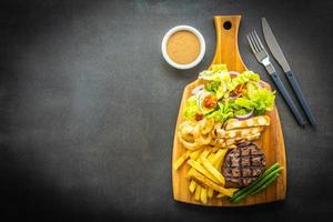 Grilled beef steak with french fries, sauce and fresh vegetables photo