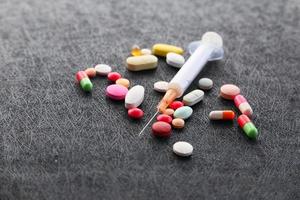 Syringe and pills on dark background photo