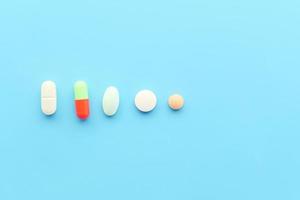 Close up of many colorful pills and capsules on blue background photo