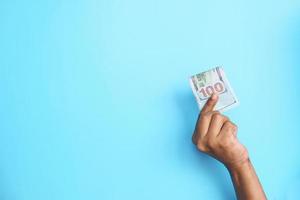 holding 100 us dollar cash on blue background photo