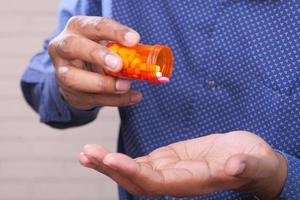 mano de hombre sosteniendo un frasco de pastillas foto