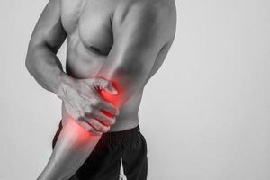 Portrait of a muscular man having elbow pain isolated on white background photo