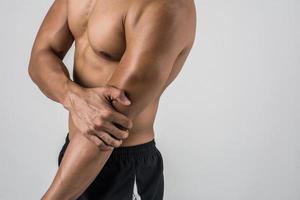 Portrait of a muscular man having elbow pain isolated on white background photo