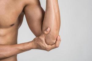 Portrait of a muscular man having elbow pain isolated on white background photo