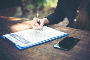 Mujer de negocios feliz firmando un documento en un escritorio trabajando en casa foto